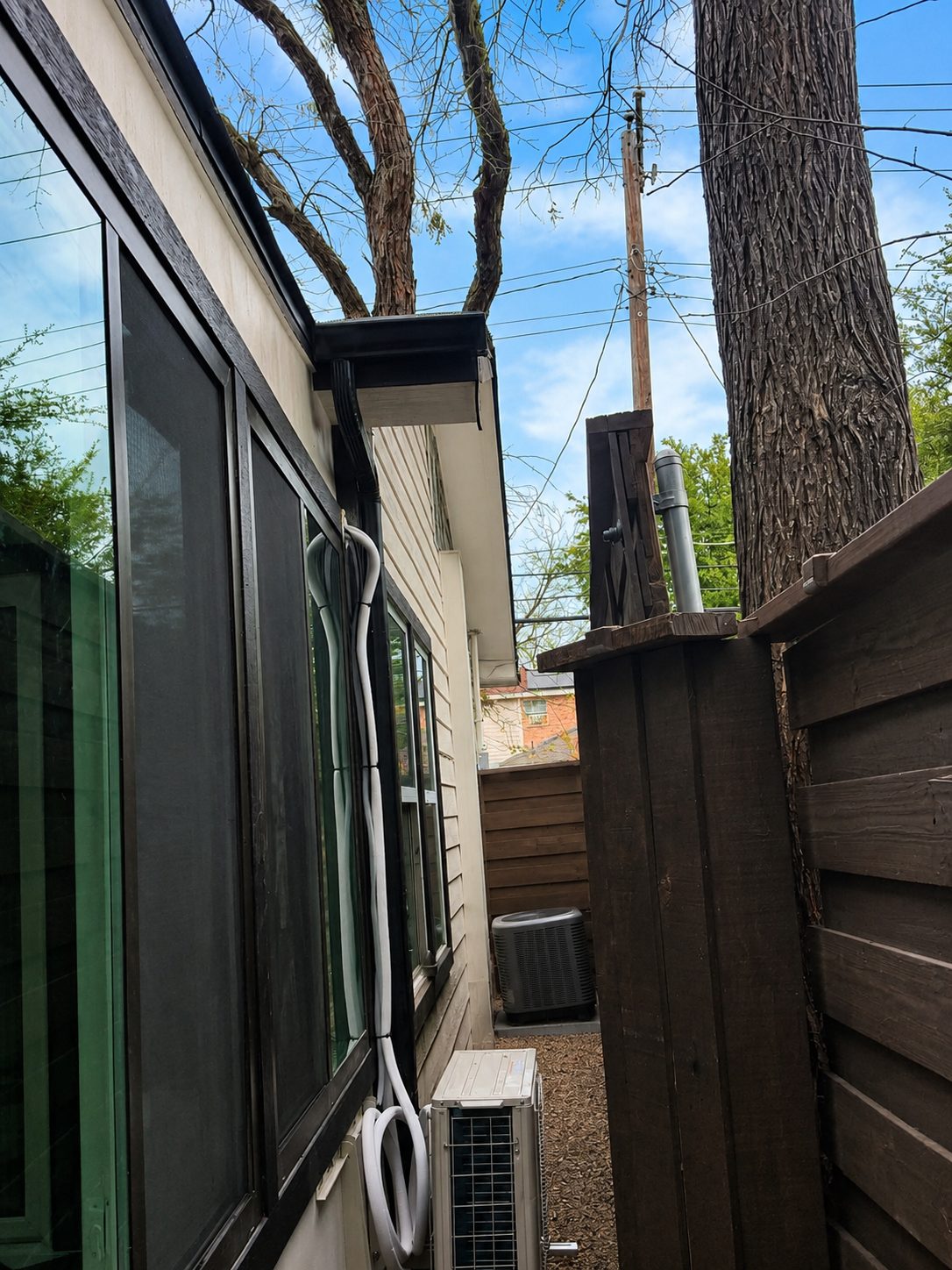 Black downspout tucked beside the windows on a narrow side yard.