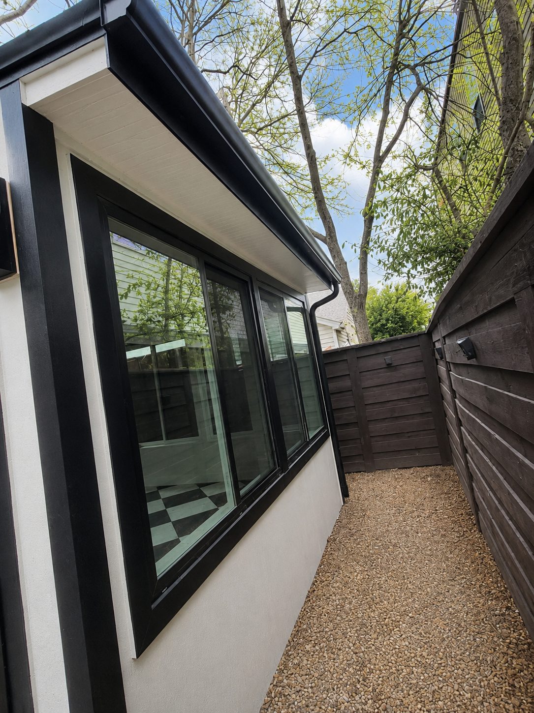 Black seamless gutter on a modern white-siding home — matched to the black window trim.