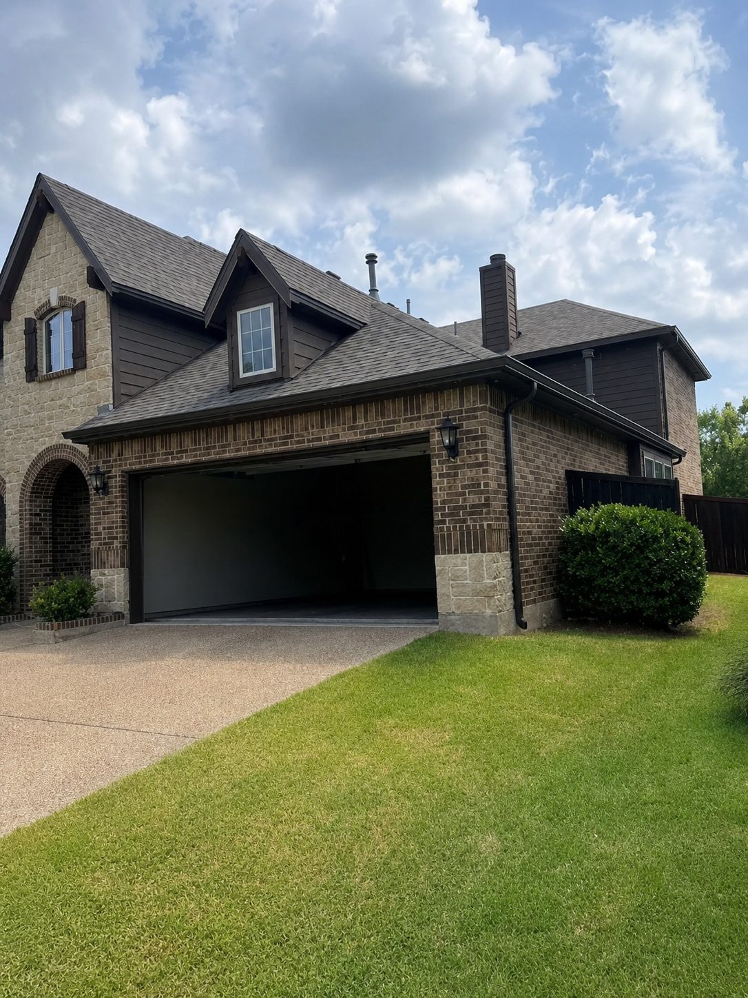 Two-story dark brick with bronze gutters and matching downspouts at the garage.