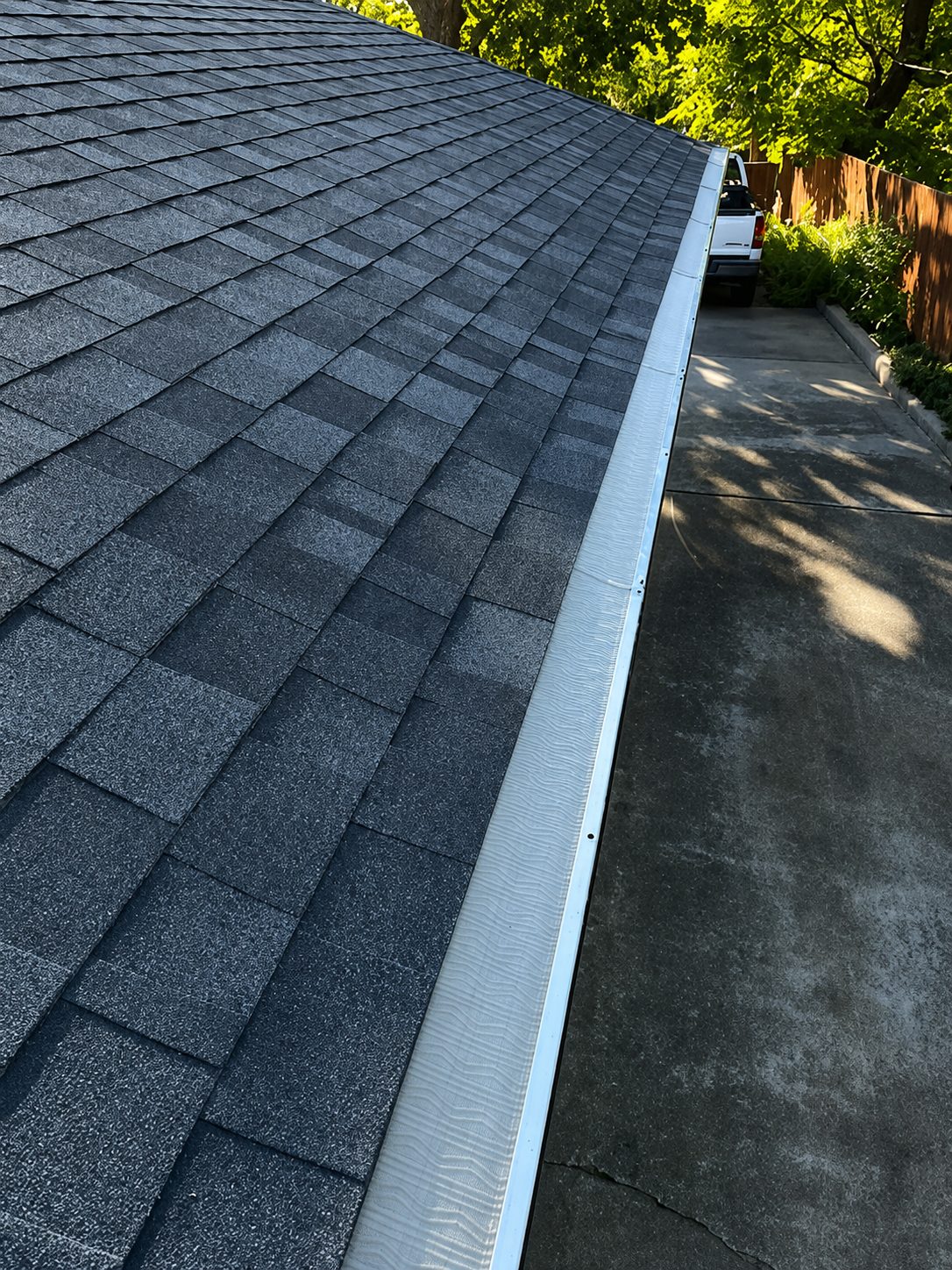 Micro-mesh guard on a white gutter, looking down the roofline to the driveway.