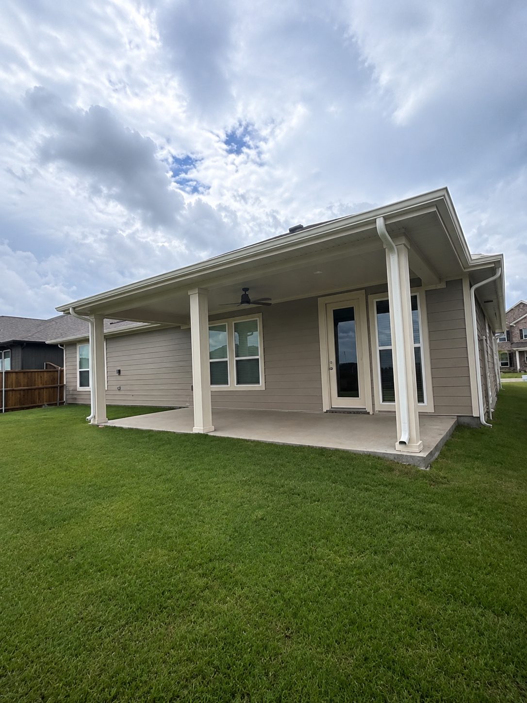 Patio cover with its own gutter and downspouts tied into the house drainage.
