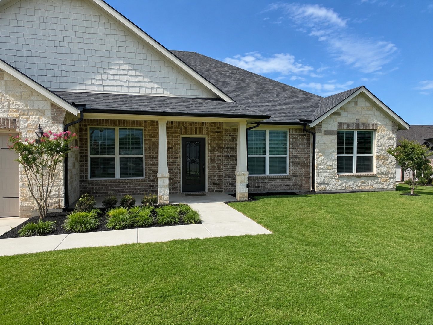 Black seamless gutters on a stone-and-brick ranch — the gutter reads as a trim line, not an add-on.