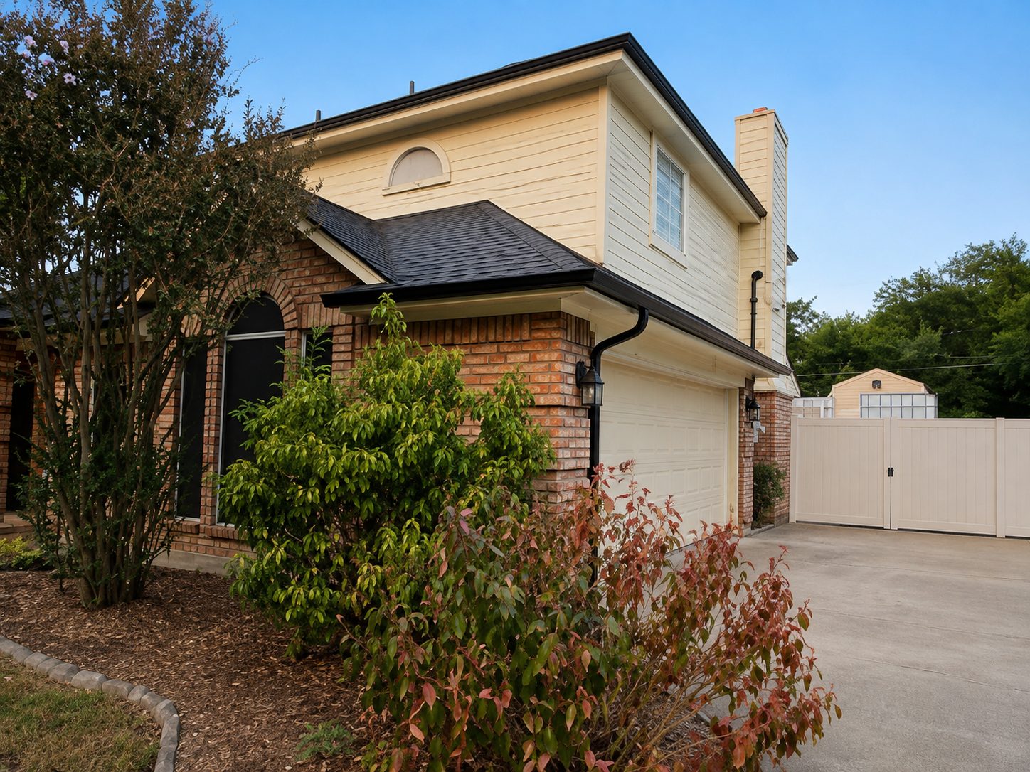 Black seamless gutters on a two-story brick and siding home with a garage